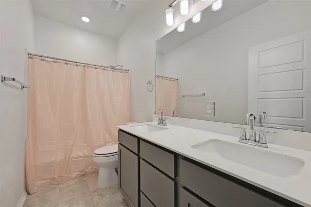a bathroom with a double vanity sink toilet and a mirror