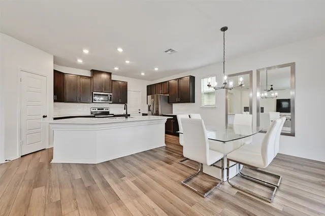 a view of kitchen with microwave a refrigerator and wooden floor
