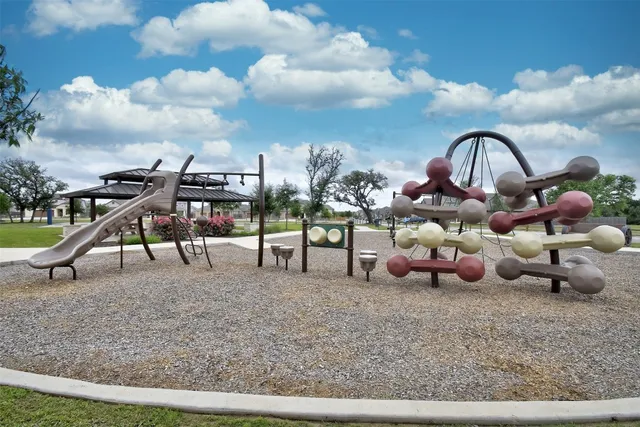 a view of a fountain in front of a house with a garden