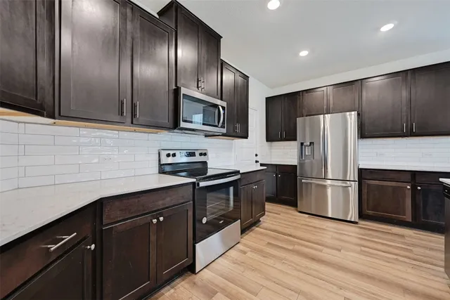 a kitchen with granite countertop wooden cabinets a refrigerator and a sink