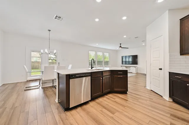 a large kitchen with stainless steel appliances granite countertop a stove top oven a sink dishwasher and a fireplace with wooden floor