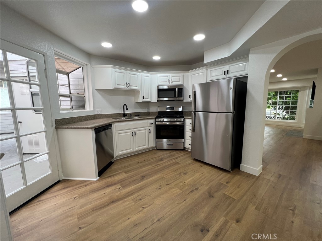 1731 East 68th Street Long Beach, CA 90805 - Photo 6 of 27 a kitchen with stainless steel appliances granite countertop a refrigerator a microwave oven a sink with wooden floors and cabinets