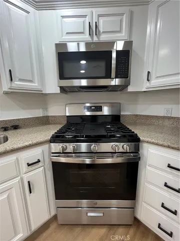 a kitchen with granite countertop white cabinets and stainless steel appliances