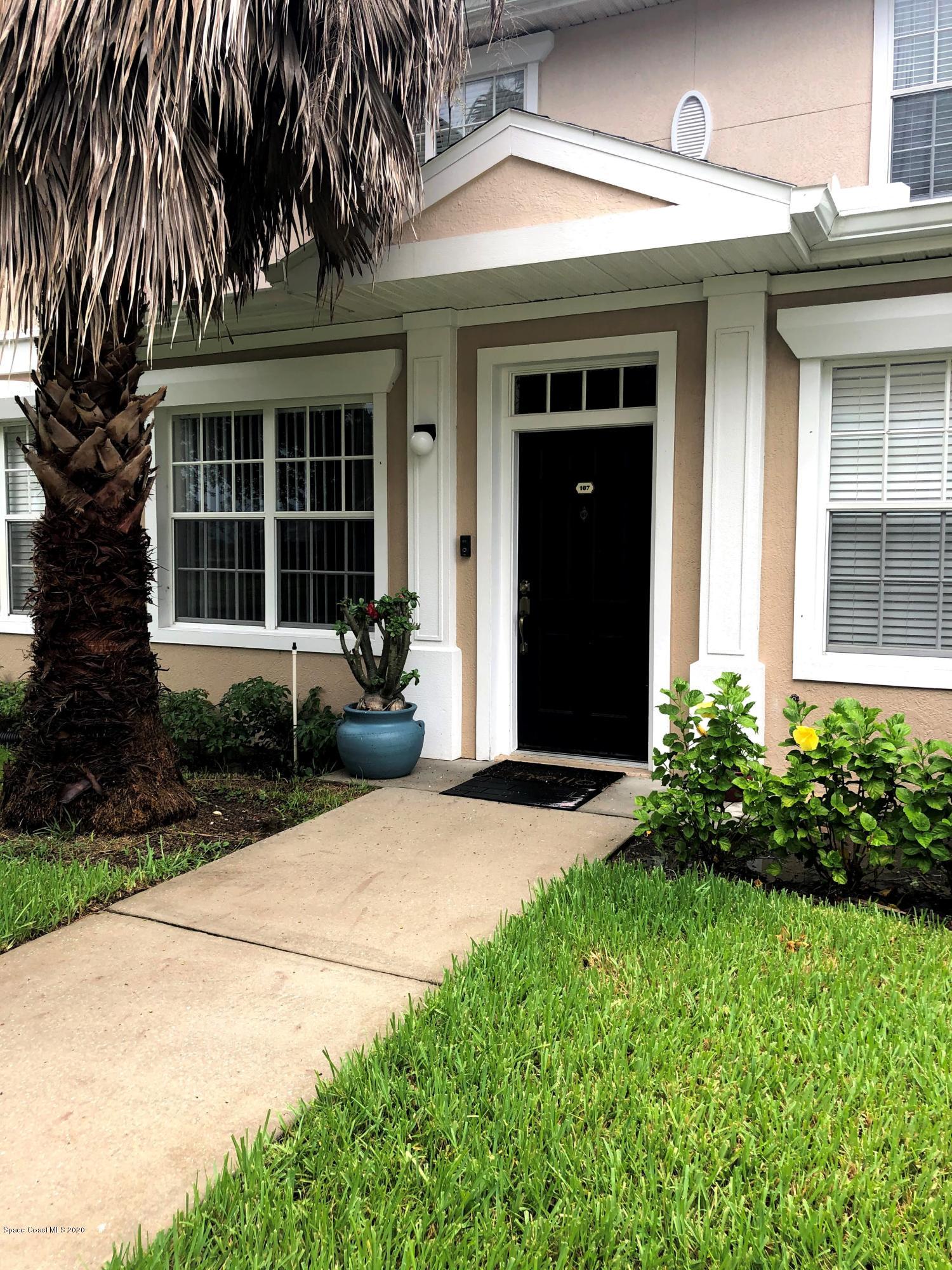 a front view of a house with a yard and potted plants