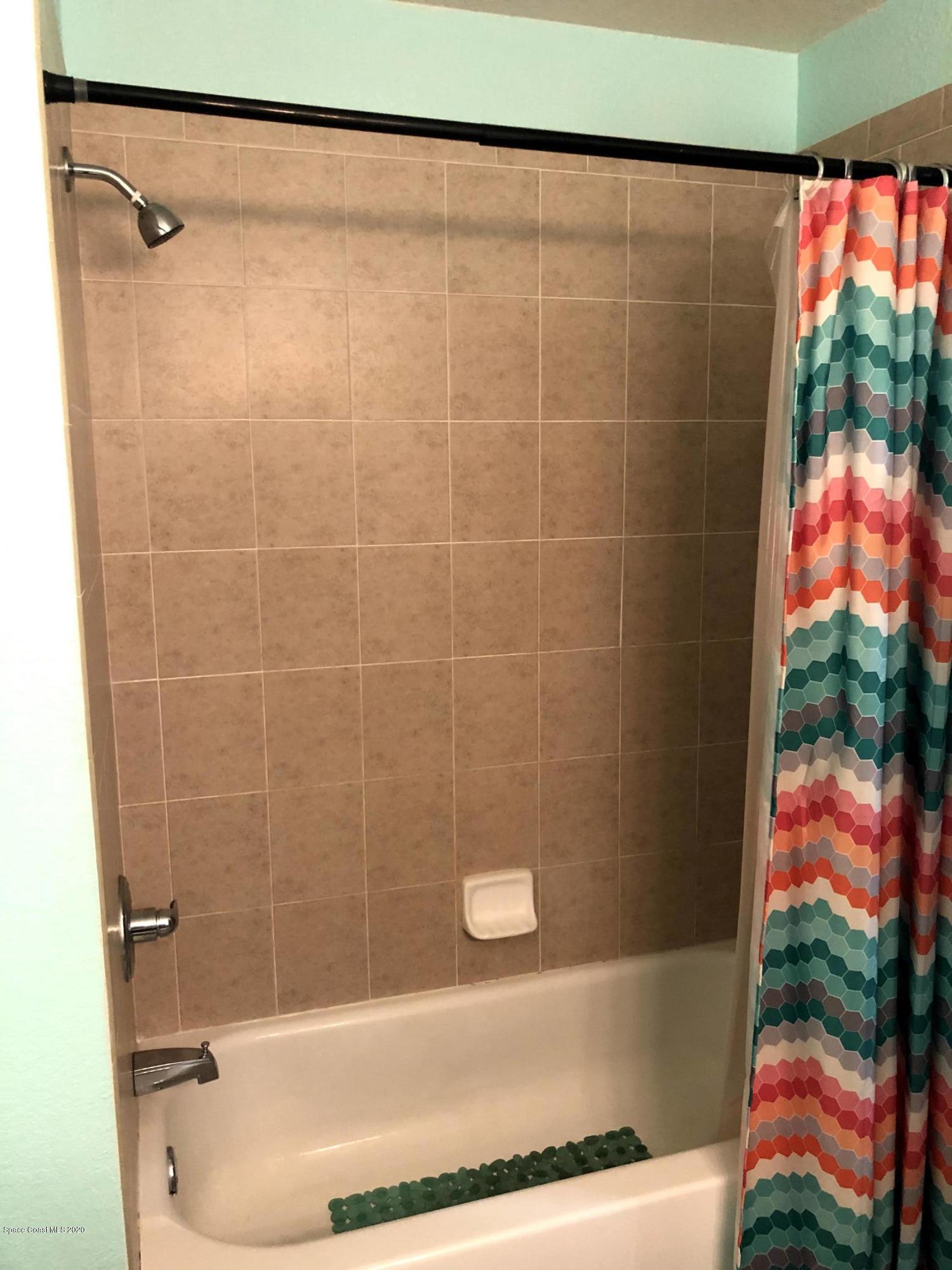 100 Turpial Way, Unit 107 Melbourne, FL 32901 - Photo 15 of 49 a bath tub sitting next to a blue shower and a sink