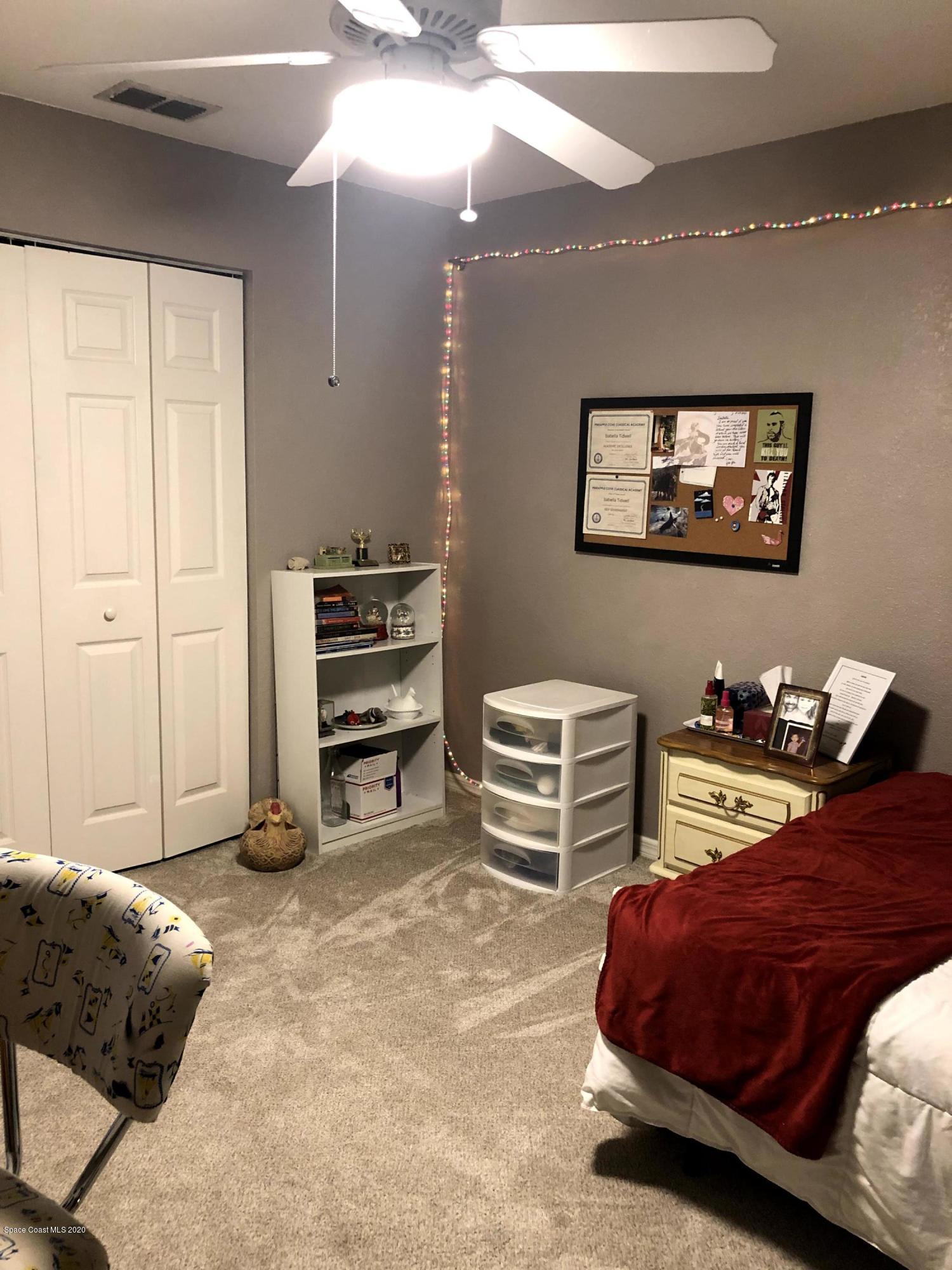 100 Turpial Way, Unit 107 Melbourne, FL 32901 - Photo 21 of 49 a bedroom with a bed and a chandelier