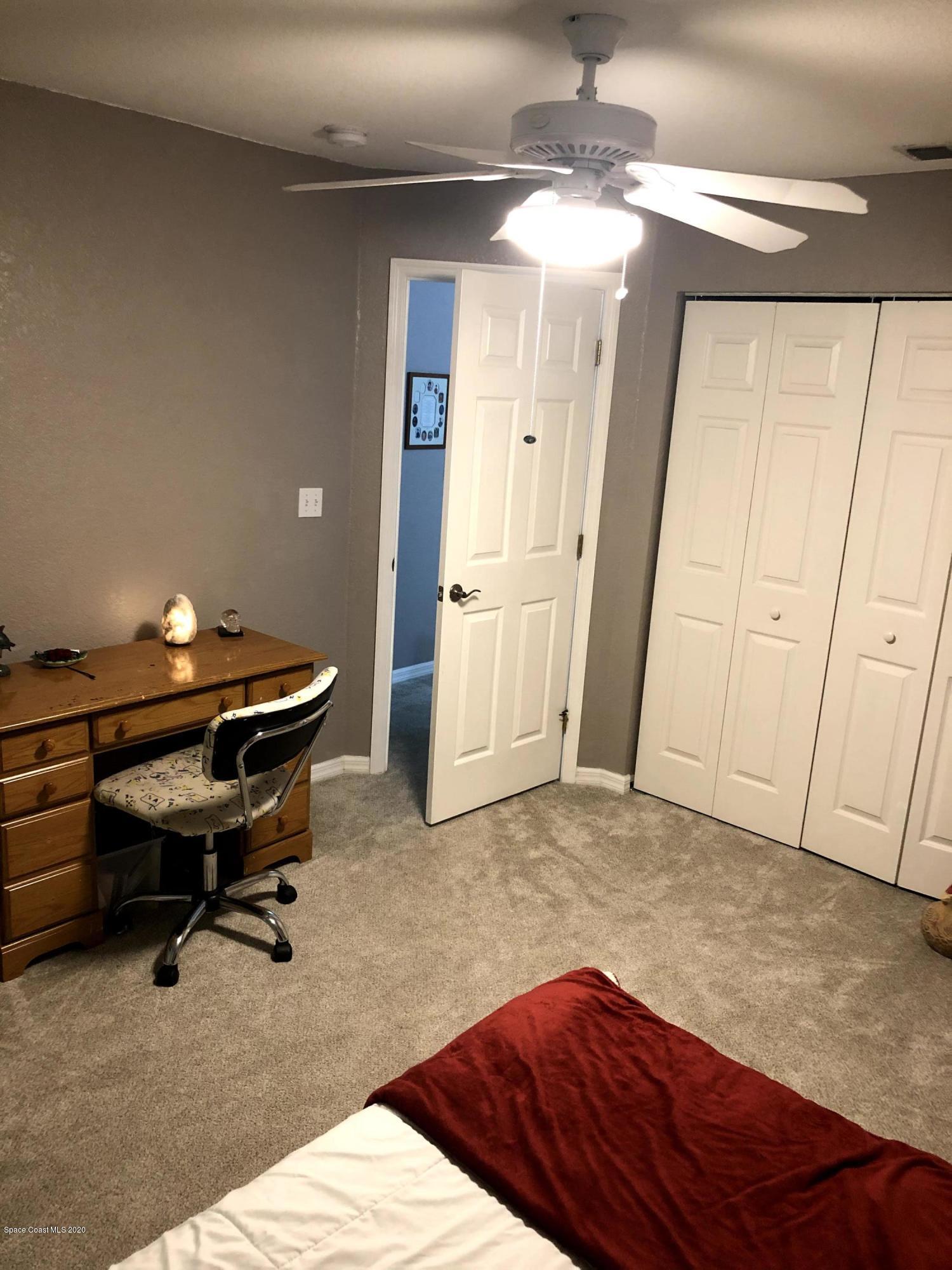 100 Turpial Way, Unit 107 Melbourne, FL 32901 - Photo 22 of 49 a bedroom with a bed and a chandelier