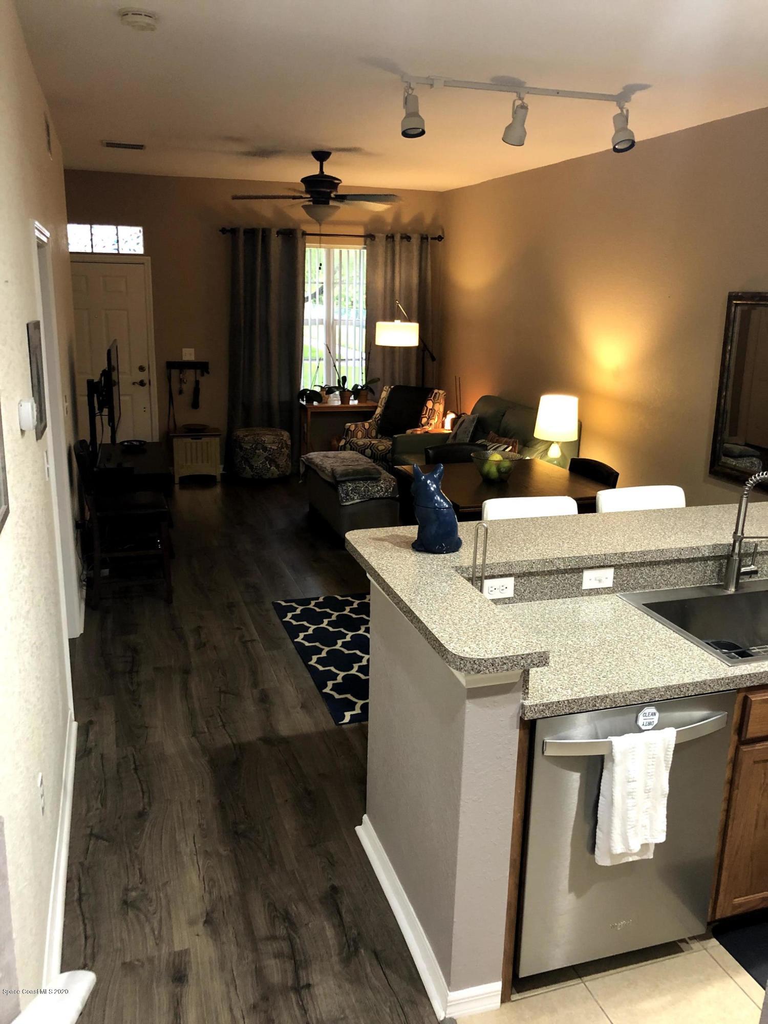 100 Turpial Way, Unit 107 Melbourne, FL 32901 - Photo 29 of 49 a view of a kitchen area kitchen island stainless steel appliances wooden floor dining table and chairs