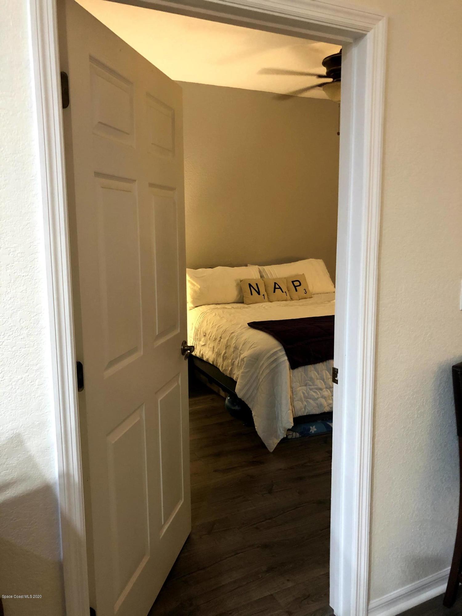 100 Turpial Way, Unit 107 Melbourne, FL 32901 - Photo 32 of 49 a bed sitting in a bedroom next to a bathroom