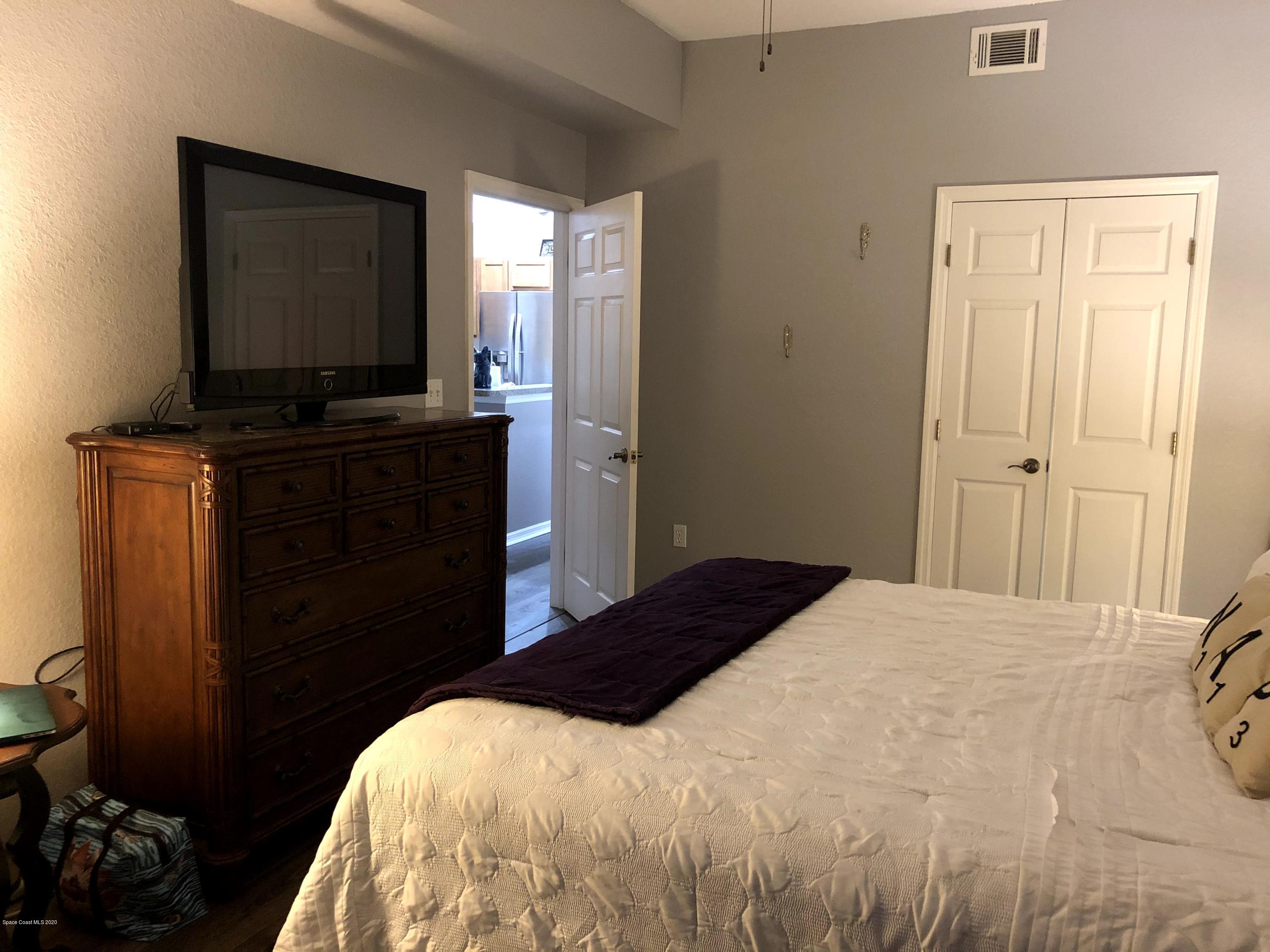100 Turpial Way, Unit 107 Melbourne, FL 32901 - Photo 35 of 49 a bedroom with a bed and flat tv screen