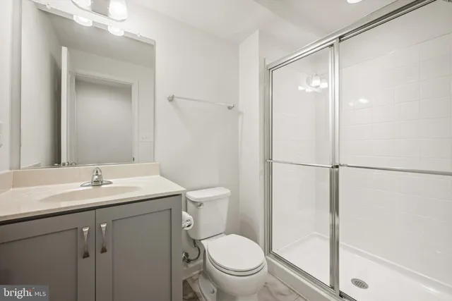 a bathroom with a shower sink vanity mirror and toilet