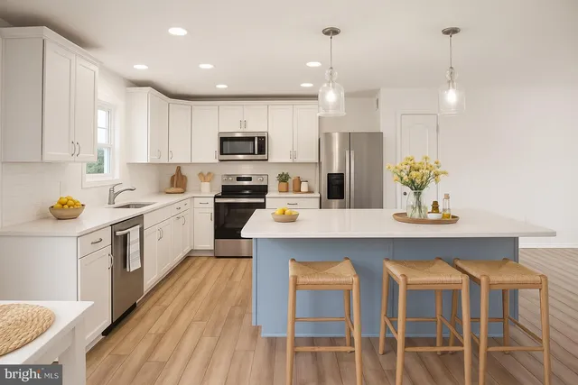 a kitchen with stainless steel appliances kitchen island granite countertop a table chairs sink and cabinets