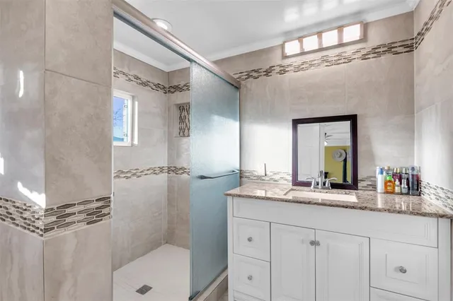 a bathroom with a granite countertop sink mirror and a shower