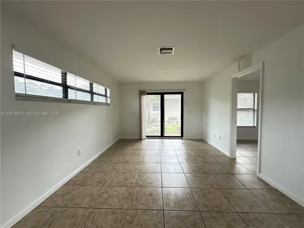 a view of an empty room with window and chandelier fan