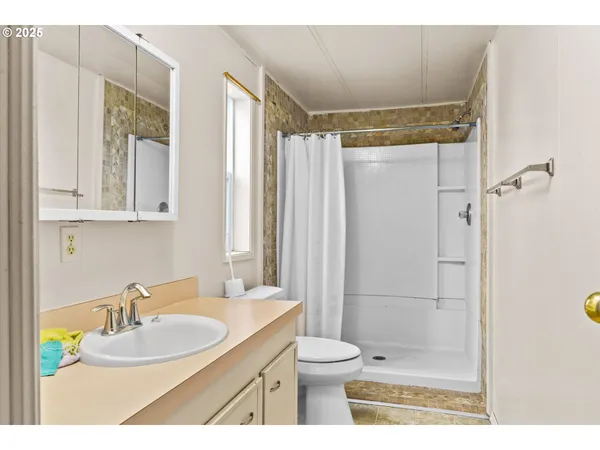 a bathroom with a granite countertop sink toilet a mirror a shower and vanity