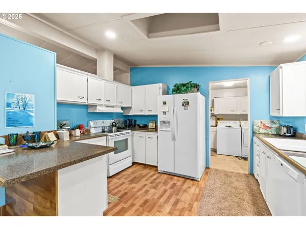 a kitchen with refrigerator a stove a sink dishwasher and white cabinets with wooden floor