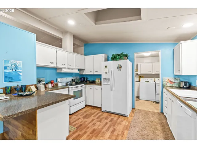 a kitchen with refrigerator a stove a sink dishwasher and white cabinets with wooden floor