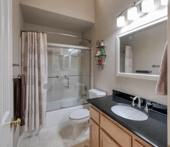 a bathroom with a granite countertop sink toilet a mirror and shower