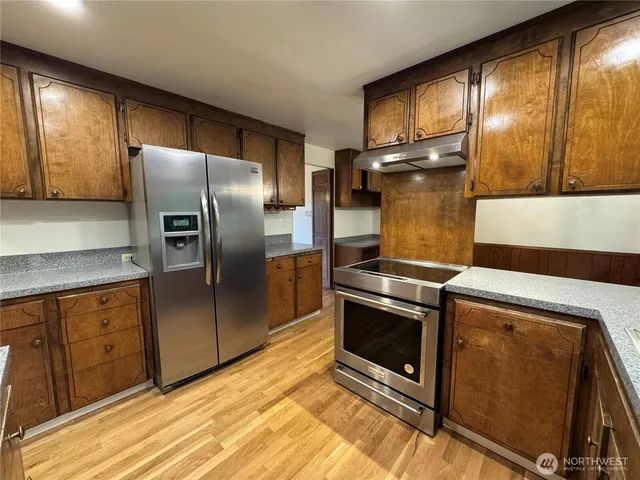 a kitchen with stainless steel appliances granite countertop a refrigerator a sink a stove and island