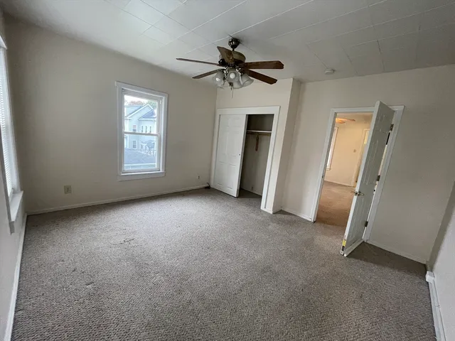 an empty room with windows and ceiling fan