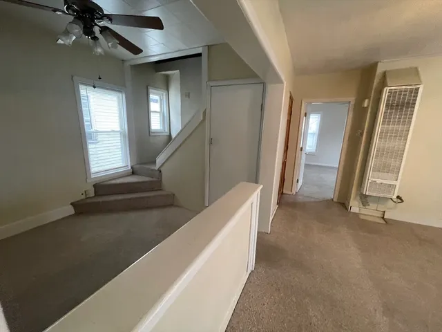 a view of an empty room with stairs and a window
