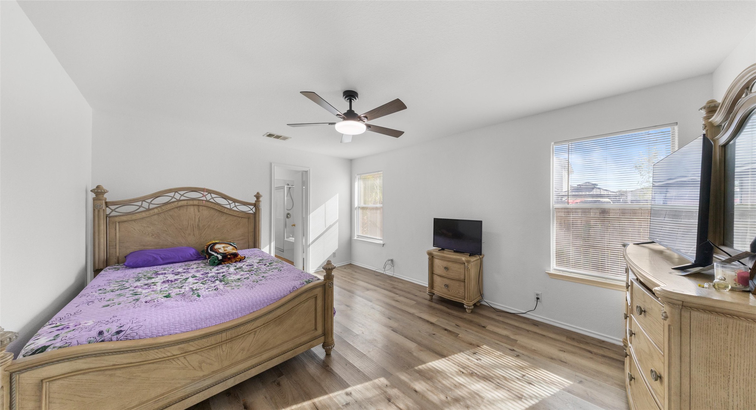 248 Endeavour Kyle, TX 78640 - Photo 11 of 32 Bedroom featuring light wood-style flooring, multiple windows, a ceiling fan, and ensuite bathroom