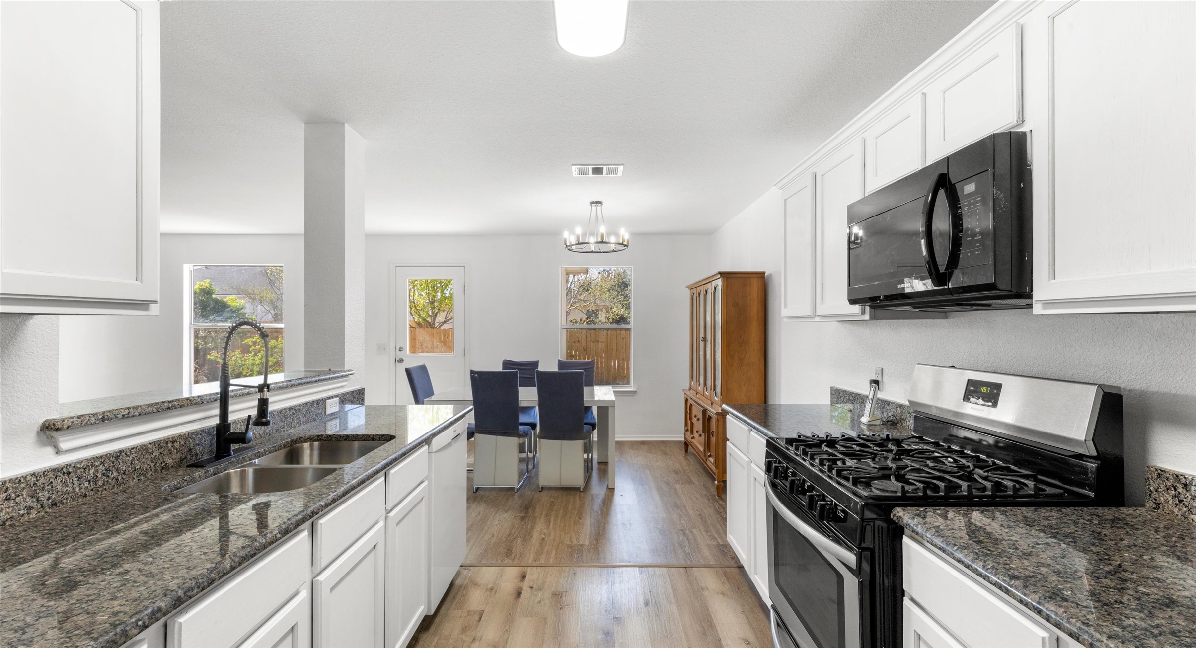248 Endeavour Kyle, TX 78640 - Photo 7 of 32 Kitchen featuring gas range, dark stone countertops, black microwave, and white cabinets