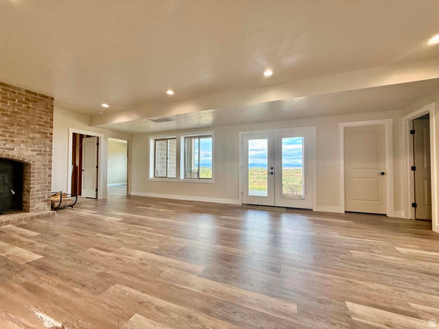2101 Goose Ranch Road Vernal, UT 84078 - Photo 40 of 72 Spacious room featuring wood-finish flooring, a brick fireplace, recessed lighting, and double glass doors opening to outdoor scenery