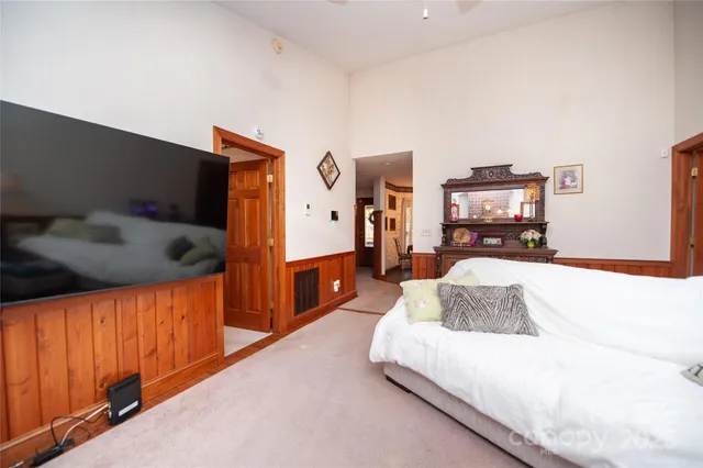a bedroom with a bed couch chandelier and a flat tv screen