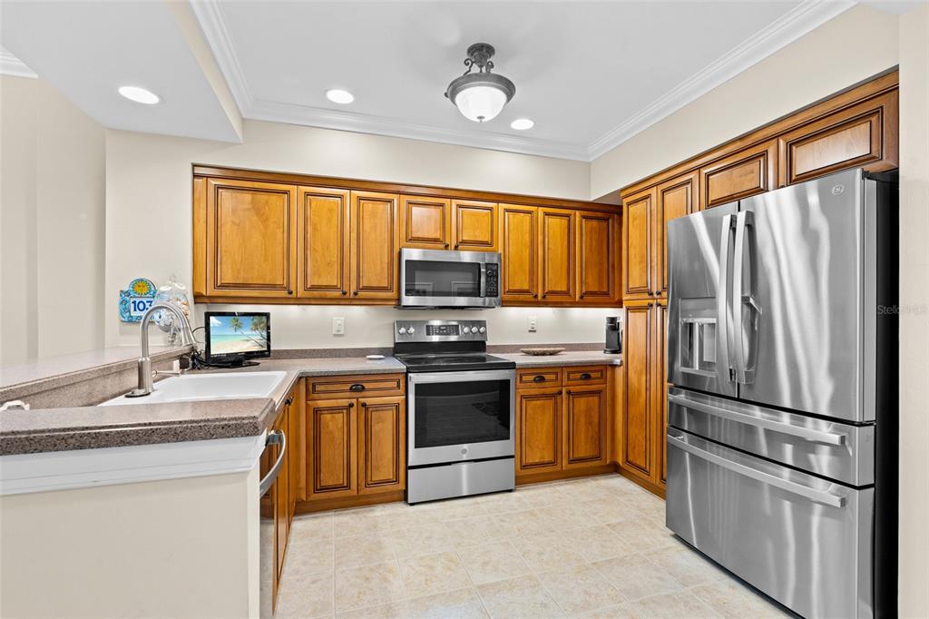 3191 Matecumbe Key Road, Unit 103 Punta Gorda, FL 33955 - Photo 5 of 48 a kitchen with stainless steel appliances granite countertop a refrigerator a stove a sink and a microwave