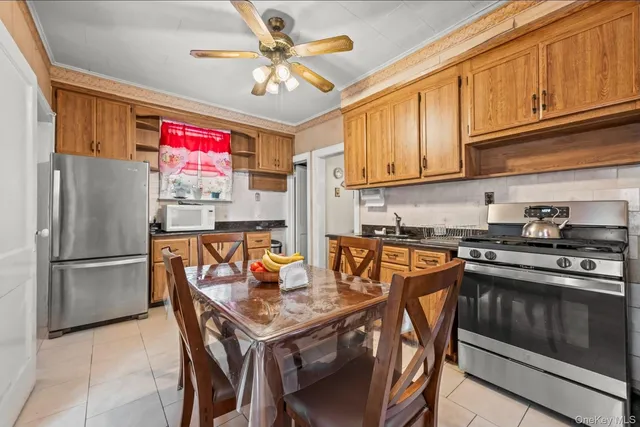 a kitchen with stainless steel appliances granite countertop a refrigerator a sink dishwasher a stove a dining table and chairs with wooden floor