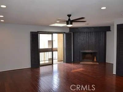 an empty room with wooden floor fireplace and windows
