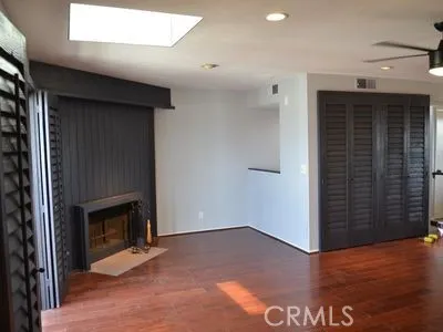 a view of an empty room with wooden floor and a fireplace
