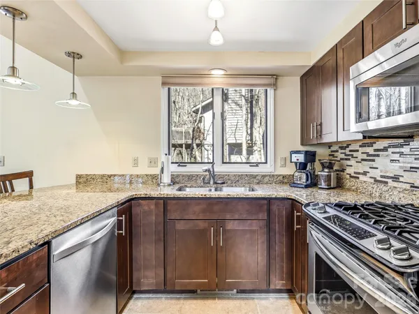 a kitchen with granite countertop a sink stove and cabinets