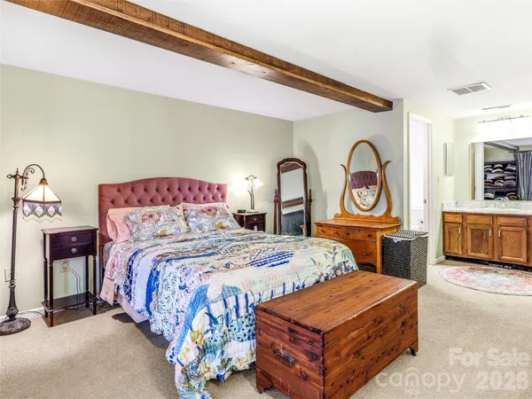 a bedroom with a bed a mirror on dresser and a chandelier