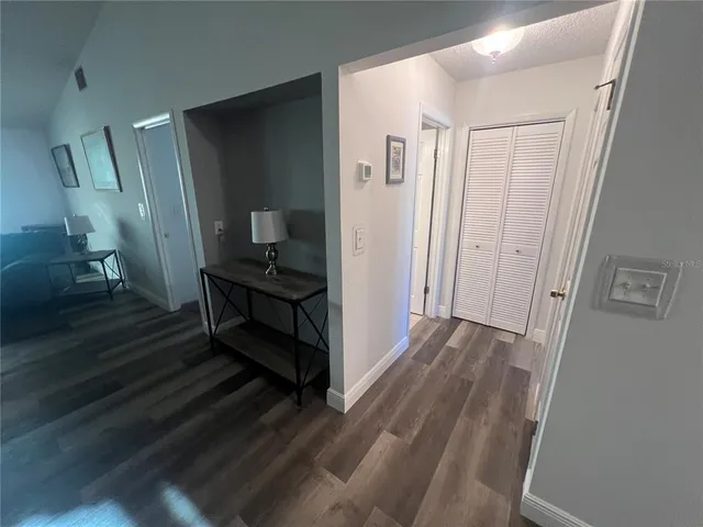a view of a hallway with wooden floor and a bathroom