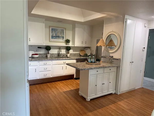 a kitchen with granite countertop a sink cabinets and wooden floor