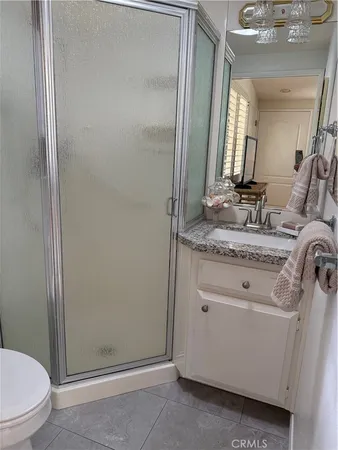 a bathroom with a granite countertop sink vanity mirror and toilet