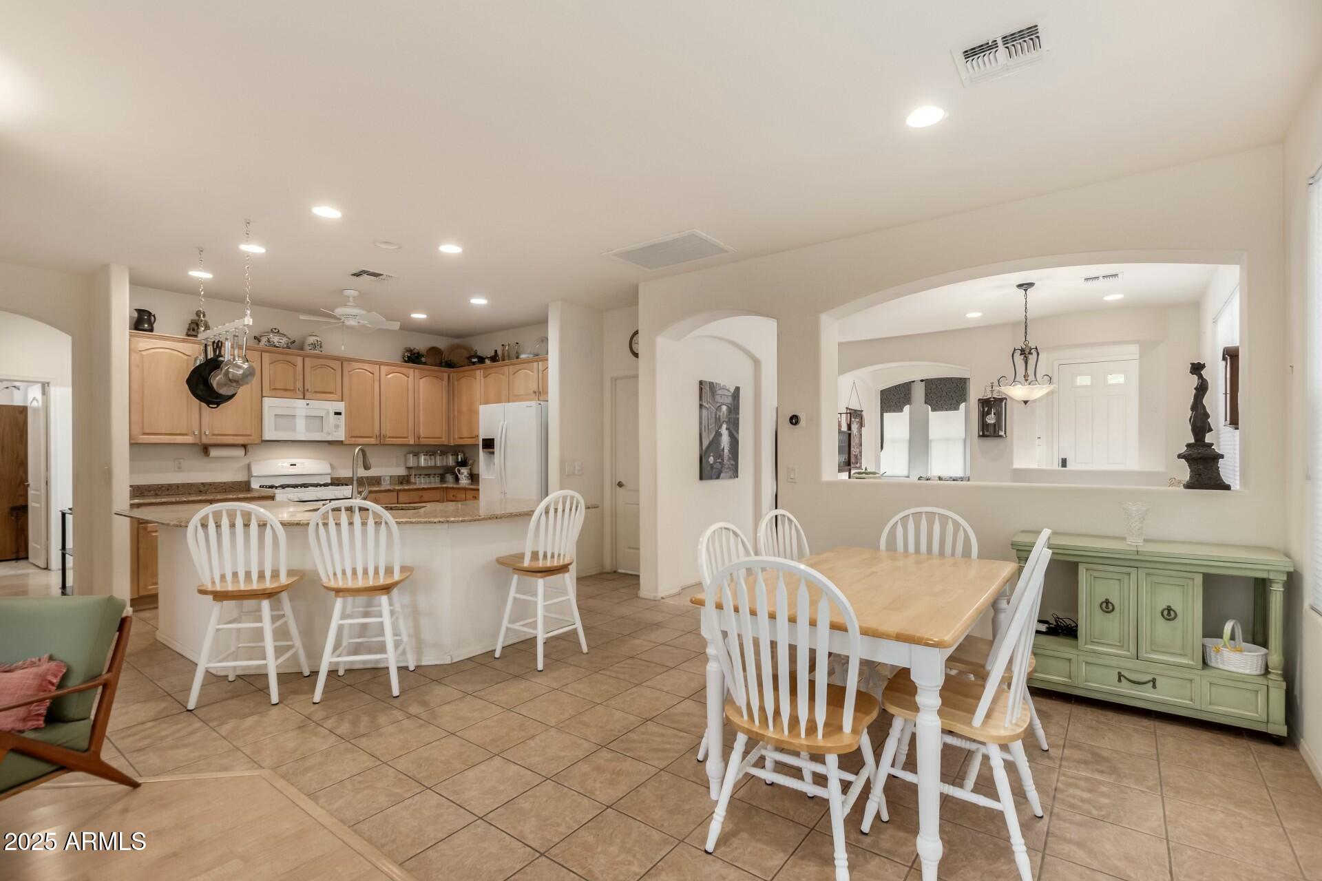 3038 West Trapanotto Road Phoenix, AZ 85086 - Photo 5 of 15 a dining area with stainless steel appliances kitchen island granite countertop a dining table chairs and view living room
