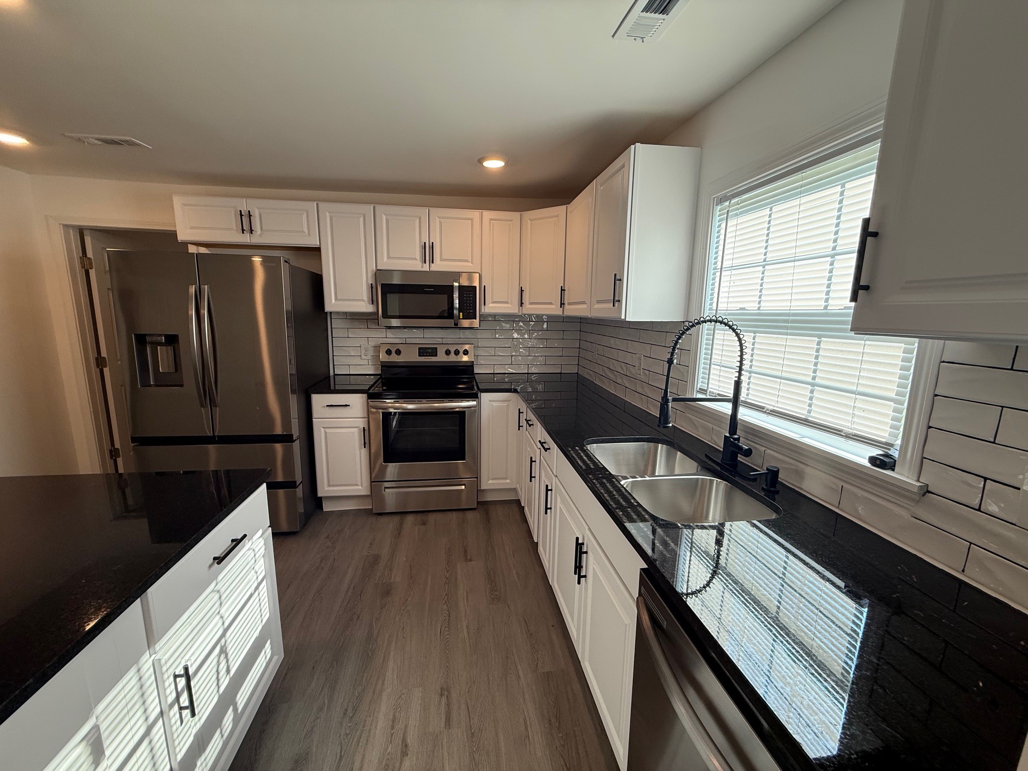 140 Phillips Street Pulaski, TN 38478 - Photo 6 of 32 a kitchen with stainless steel appliances granite countertop a stove a sink dishwasher a refrigerator white cabinets and wooden floor