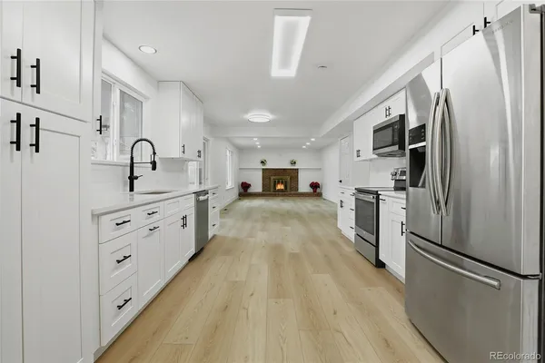 a kitchen with stainless steel appliances granite countertop a refrigerator sink and white cabinets