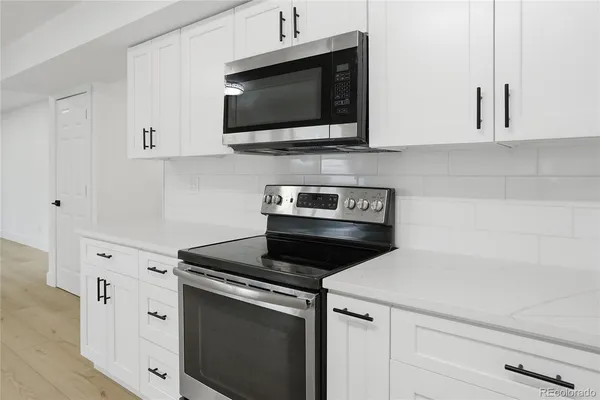 a kitchen with white cabinets and black appliances