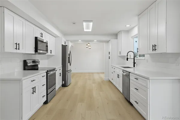 a large kitchen with stainless steel appliances granite countertop a lot of counter space and wooden floors