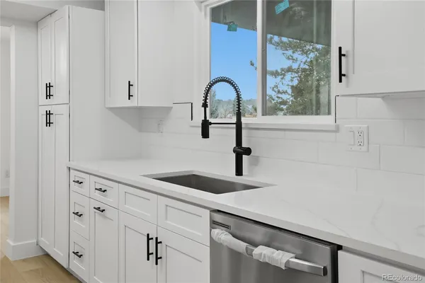 a kitchen with granite countertop white cabinets and a window