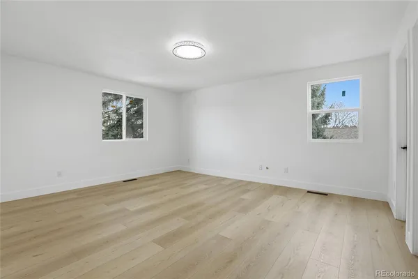 a view of an empty room with a window and a dresser