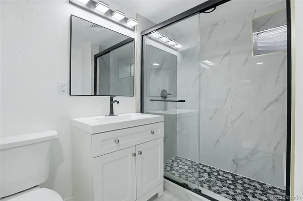 a bathroom with a sink a toilet and shower