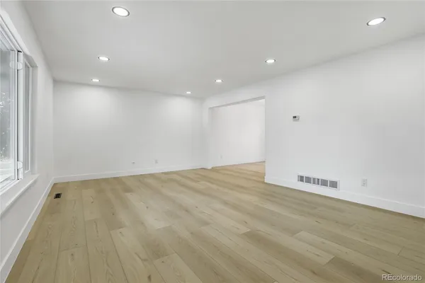 an empty room with wooden floor and windows
