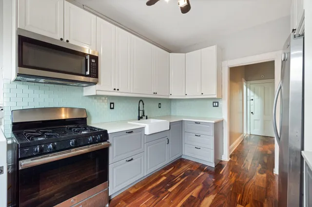 a kitchen with stainless steel appliances white cabinets and a stove top oven