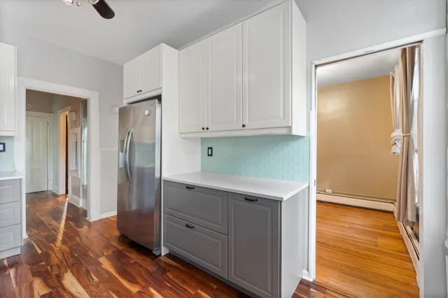 a kitchen with white cabinets and wooden floor