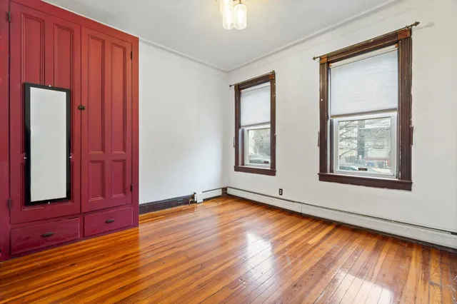 an empty room with wooden floor closet and windows